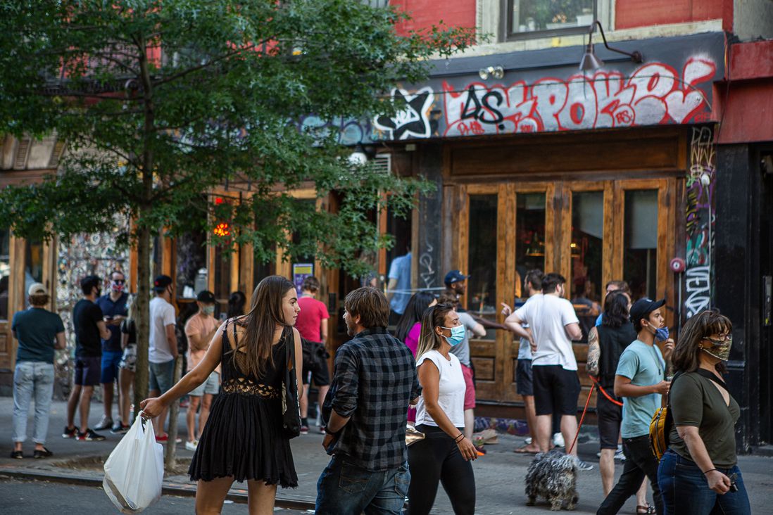 Groups of people in the streets and on the sidewalks outside of bars in the East Village